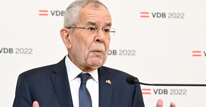 Alexander Van der Bellen bei der Verkündung seiner Wiederkandidatur. Im Hintergrund sein Logo für den Whalkampf: rot-weiß-rote Flagge VDB 2022. Er wirkt ratlos