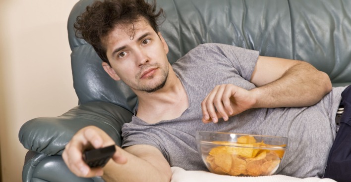 Mann liegt faul auf der Couch und schaut fern | Credit: iStock.com/lukas_zb