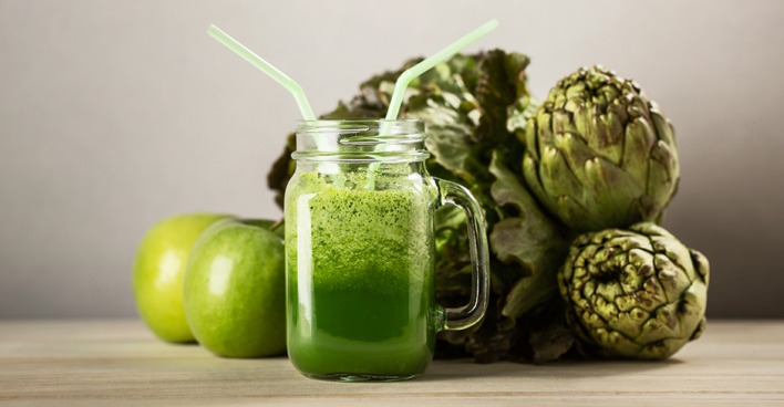 Artischocken und Äpfel arrangiert um einen grünen Smoothie | Credit: iStock.com/alexsalcedo