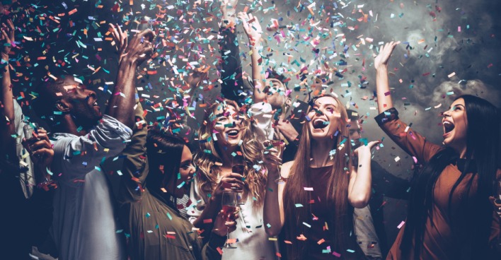 Junge Gruppe an Menschen feiert ausgelassen im Konfetti-Regen | Credit: iStock.com/g-stockstudio