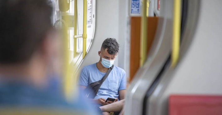 Junger Mann mit Maske in U-Bahn