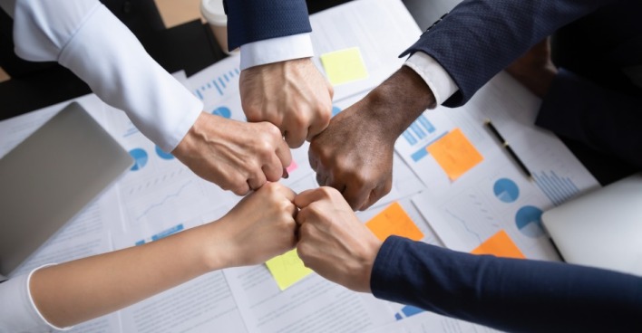 Viele Mitarbeiter bezeugen ihre Teamstärke mit Faustschlag | Credit: iStock.com/fizkes