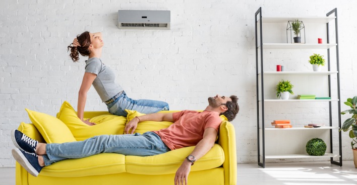 Mann und Frau liegen auf einer Couch unter einer Klimaanlage | Credit: iStock.com/LightFieldStudios