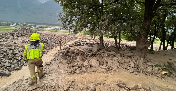 Eine Mure ist abgegangen. Ein Feuerwehrmann steht im Schlamm