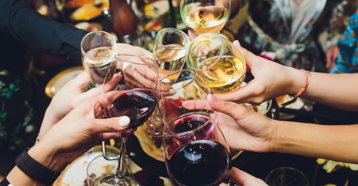 Mehrere Hände, die mit Wein- und Sektgläsern anstoßen.