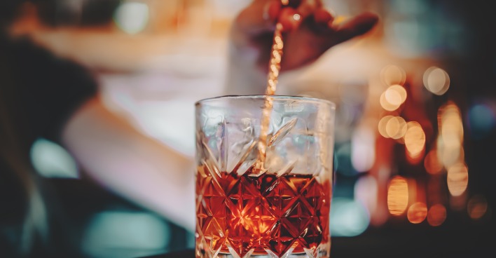 Glas mit Rührstäbchen und rotem Cocktail Negroni