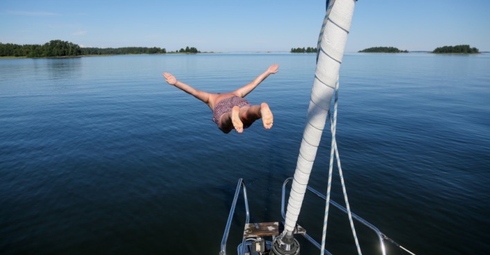 Mann springt von Boot in Vänern See in Schweden. | Credit: unsplash