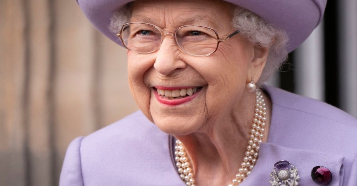 Queen Elizabeth II. in einem lila Kostüm