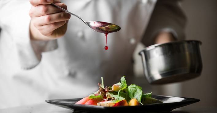 Ein Koch veredelt eine Mahlzeit mit einer Soße