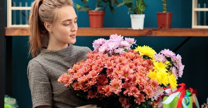 Junge Frau mit Chrysanthemen in der Hand | Credit: iStock.com/Svyatoslav Balan