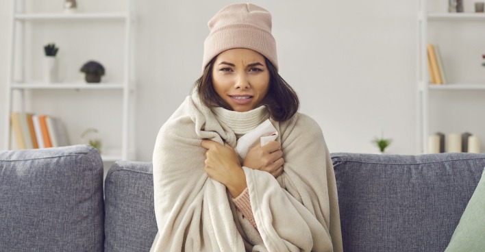 Frierende Frau auf der Couch | Credit: iStock.com/Lacheev
