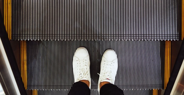 Mann mit weißen Schuhen auf einer Rolltreppe | Credit: iStock.com/toncd32