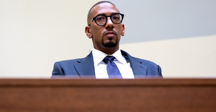 Fußballprofi Jerome Boateng sitzt, in einen eleganten Anzug gekleidet, auf der Anklagebank eines Gerichtssaals