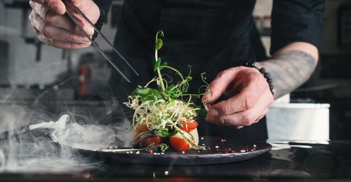Koch richtet Salat an. | Credit: iStock.com/MykolaSenyuk