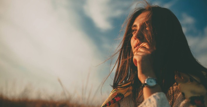 Junge Frau blickt nachdenklich in die Landschaft | Credit: iStock.com/max-kegfire