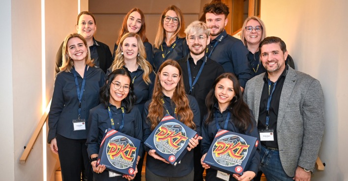 Das Team von APS Personal mit dem Wirtschaftsspiel: (vorne) Joan-Mae Armenio, Jennifer Zadra, Julia Degold, (mitte) Marina Plesa, Melanie Berthold, Patrick Pfister und Martin Hagen (Geschäftsführer) und (hinten) Isabel Fridrich, Iris König, Petra Rasser-Spiegel, Marco Moosmann und Sonja Graf