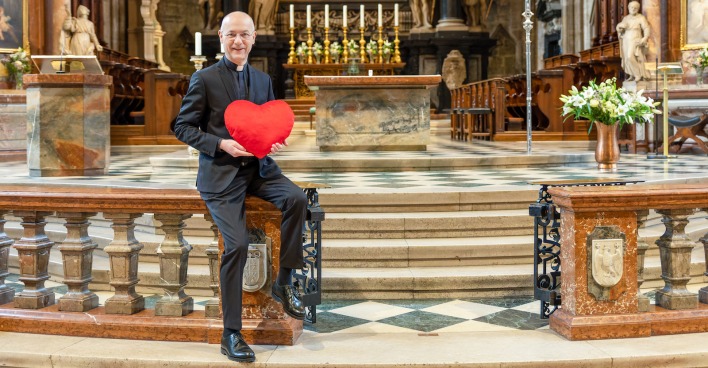 Dompfarrer Toni Faber hält am Altar ein Valentins-Herz| Credit: Stephan Schönlaub