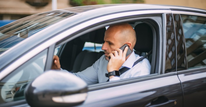Mann telefoniert während des Autofahrens ohne Freisprechanlage.
