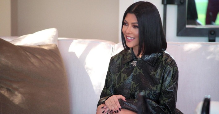 Kourtney Kardashian sitzt auf einer weißen Couch.