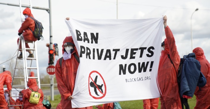 Klima-Aktivisten zeigen ein Transparent mit der Aufschrift "Ban Private Jets Now"
