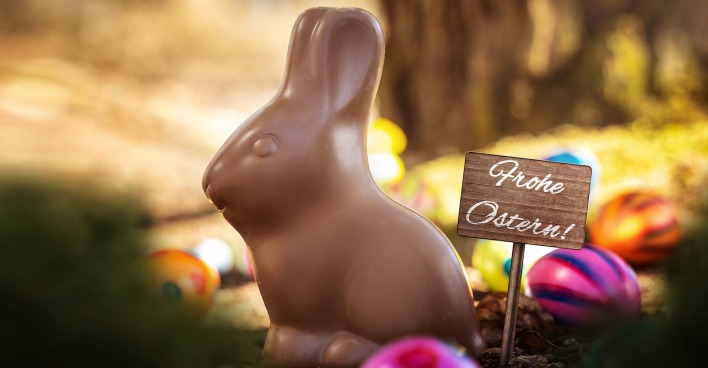 Ein Schoko-Osterhase und ein Schild, auf dem "Frohe Ostern" steht.