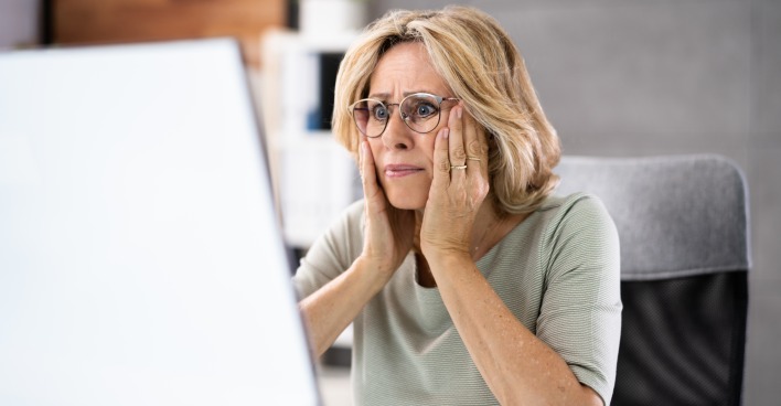 Ältere Frau erschrocken vor Laptop