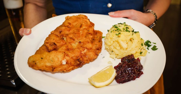 Ein Schnitzel mit Preisselbeermarmelade und Kartoffelsalat.