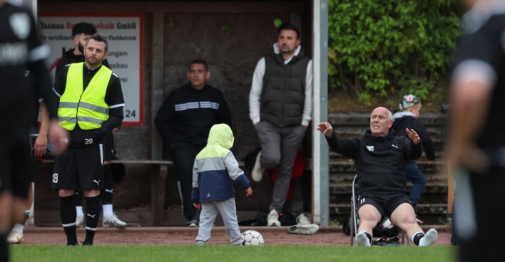 Mario Basler, der rauchend auf einem Klappstuhl am Spielfeldrand sitzt und die Beine von sich streckt