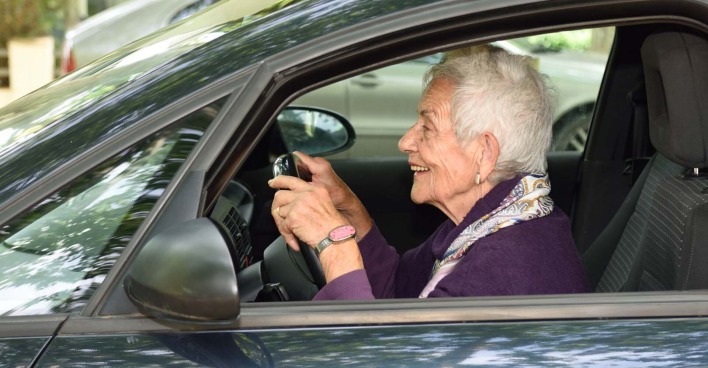 Alte Frau sitzt am Steuer ihres Autos