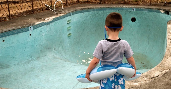 Kind steht vor leerem Schwimmbecken