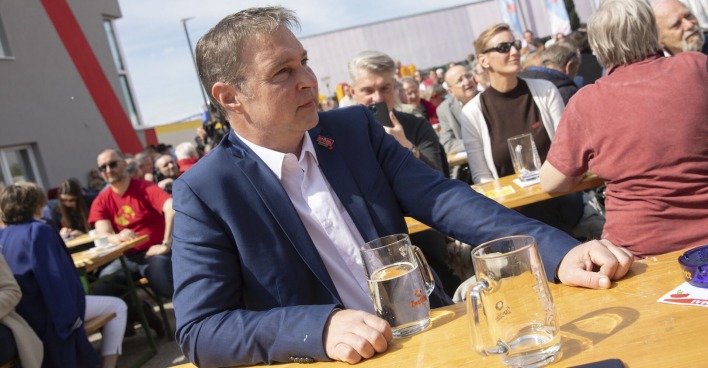 Andi Babler sitzt an einer Bierbank im Freien, hinter ihm Menschen. Vor ihm steht ein großer Spritzer