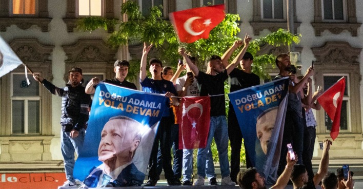 Aufnahme bei Nacht. Jugendliche und junge Männer schwenken ausgelassen türkische Fahnen und hissen Transparente mit Erdogans Porträt.