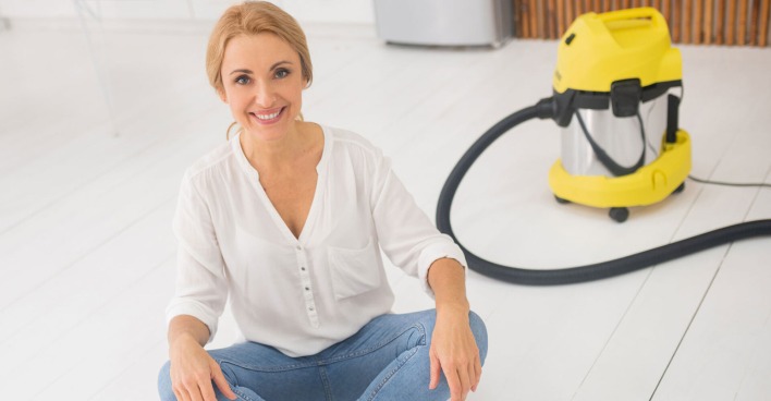 Junge Frau sitzt im Schneidersitz vor ihrem Nass-/Trockensauger | Credit: iStock.com/Zinkevych