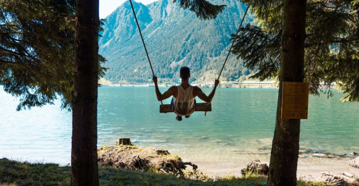 Junger Mann schaukelt man Ufer des Lago di Poschiavo | Credit: Valposchiavo Turismo