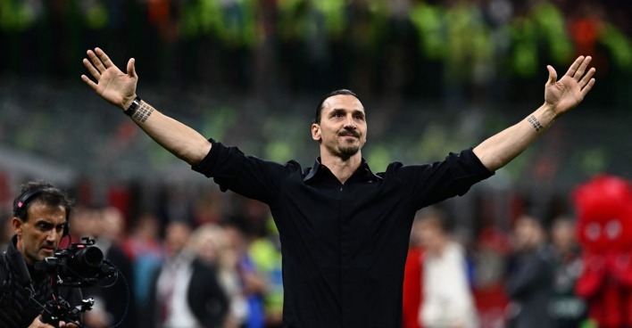 Der ganz in schwarz gekleidete Zlatan Ibrahimović mit weit ausgebreiteten Armen vor der Kulisse des Heimstadions des AC Milan