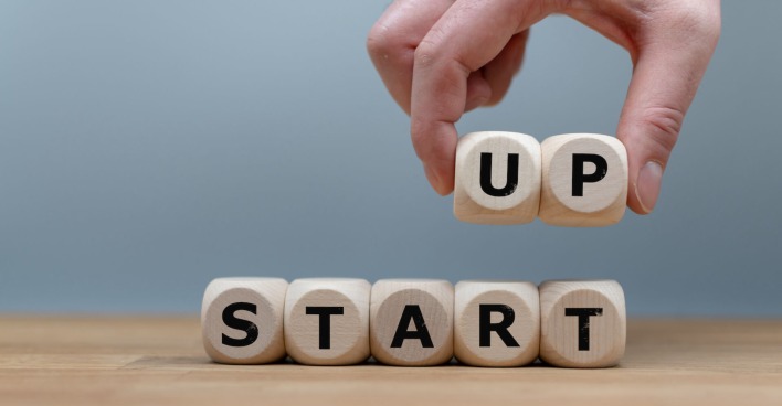 Hand von oben arrangiert Buchstaben aus Holz zuStart-Up