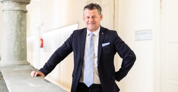 Bürgermeister Scheider, in Anzung und mit einer Krawatte, hinter einer Balustrade im Klagenfurter Rathaus