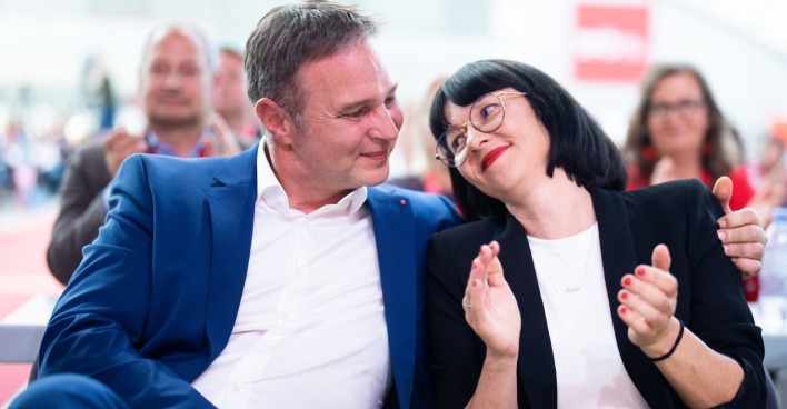 Babler sitzt neben seiner Lebensgefährtin und hat den Arm um sie. Die beiden schauen sich verliebt an.