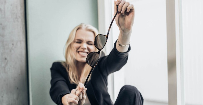 Frau zeigt, dass die Brille unzerbrechlich ist und in alle Richtungen gebogen werden kann