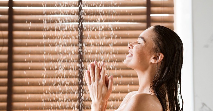 Frau unter dem Wasserstrahl einer Dusche.