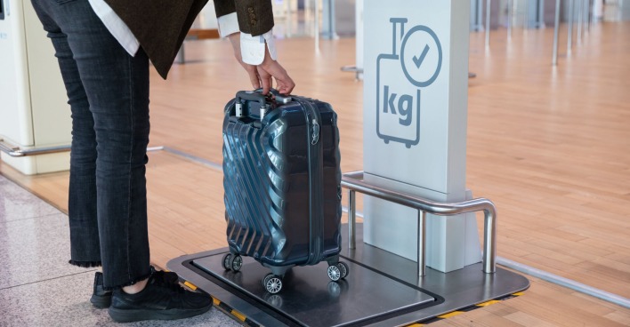 Eine Frau wiegt am Flughafen ihren Koffer.