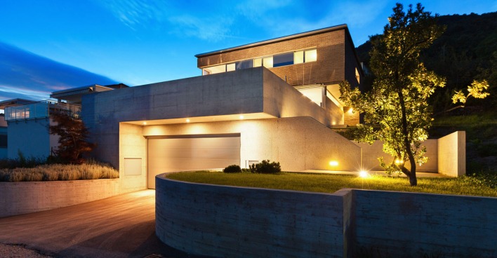 Beleuchtetes modernes Wohnhaus in der Abenddämmerung | Credit: iStock.com/piovesempre
