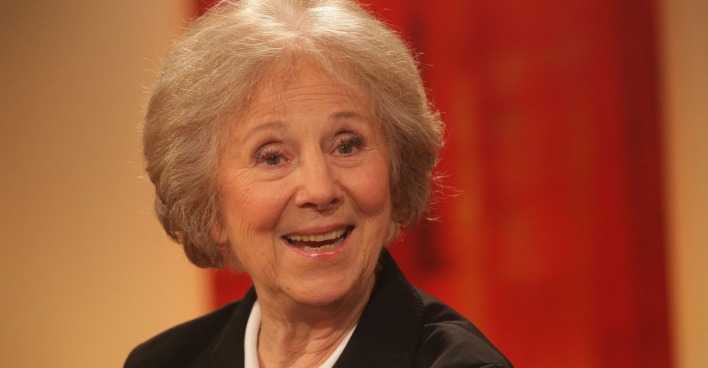 Eine ältere Dame mit weißblonden Haaren lacht in die Kamera.