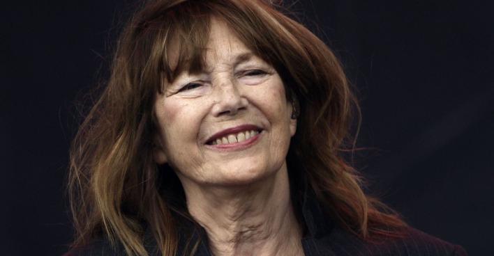 Eine ältere Frau mit braunen Haaren und schwarzem Hintergrund.
