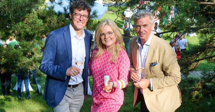 Zwei Männer und eine Frau lächeln beim Sommerfest im Garten der Sektkellerei Schlumberger| Credit:  Sabine Klimpt
