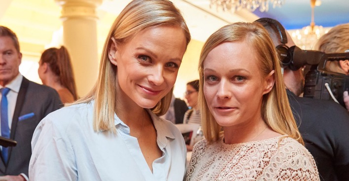 Zwei junge Frauen mit blonden Haaren lachen in die Kamera.