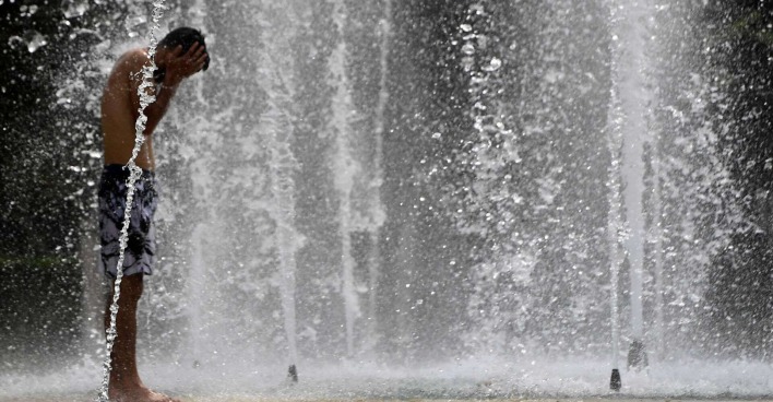 Bub kühlt sich in einem Brunnen ab.