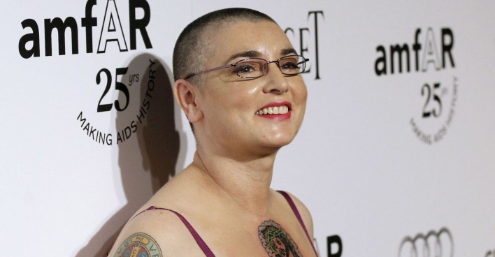 Sinéad O'Connor lächelnd mit kurzen Haaren und Brille.