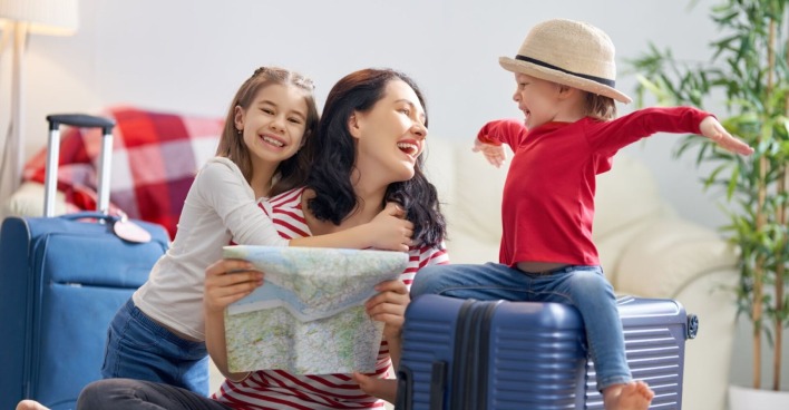 Mutter und zwei Kinder planen den Urlaub | Credit: iStock.com/Choreograph