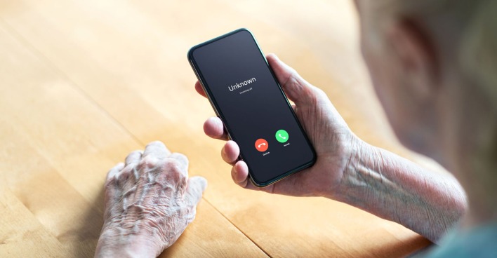 Ältere Frau mit einem Smartphone wir von einem unbekannten Anrufer angerufen.